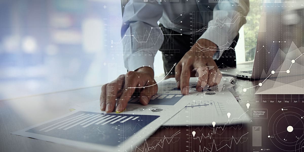 man's hands over printed graphs on a desk with graph images in the foreground